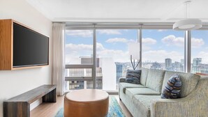 Uma sala de estar moderna com uma janela grande, um sofá, uma mesa de centro e uma televisão de tela plana.