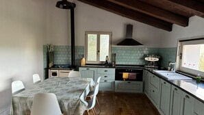Una cocina con una mesa de comedor, sillas, una estufa y un ventanal.