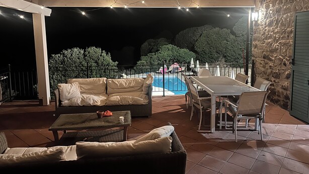 Un patio al aire libre con piscina, asientos e iluminación con guirnaldas.