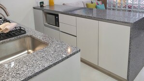 A modern kitchen with granite countertops, stainless steel appliances, pendant lighting, and a large window with a view. - Ortega Living (Guadalajara)