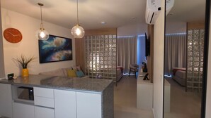 A modern kitchen with a built-in island, pendant lighting, a clock, and a large window with a view. - Ortega Living (Guadalajara)