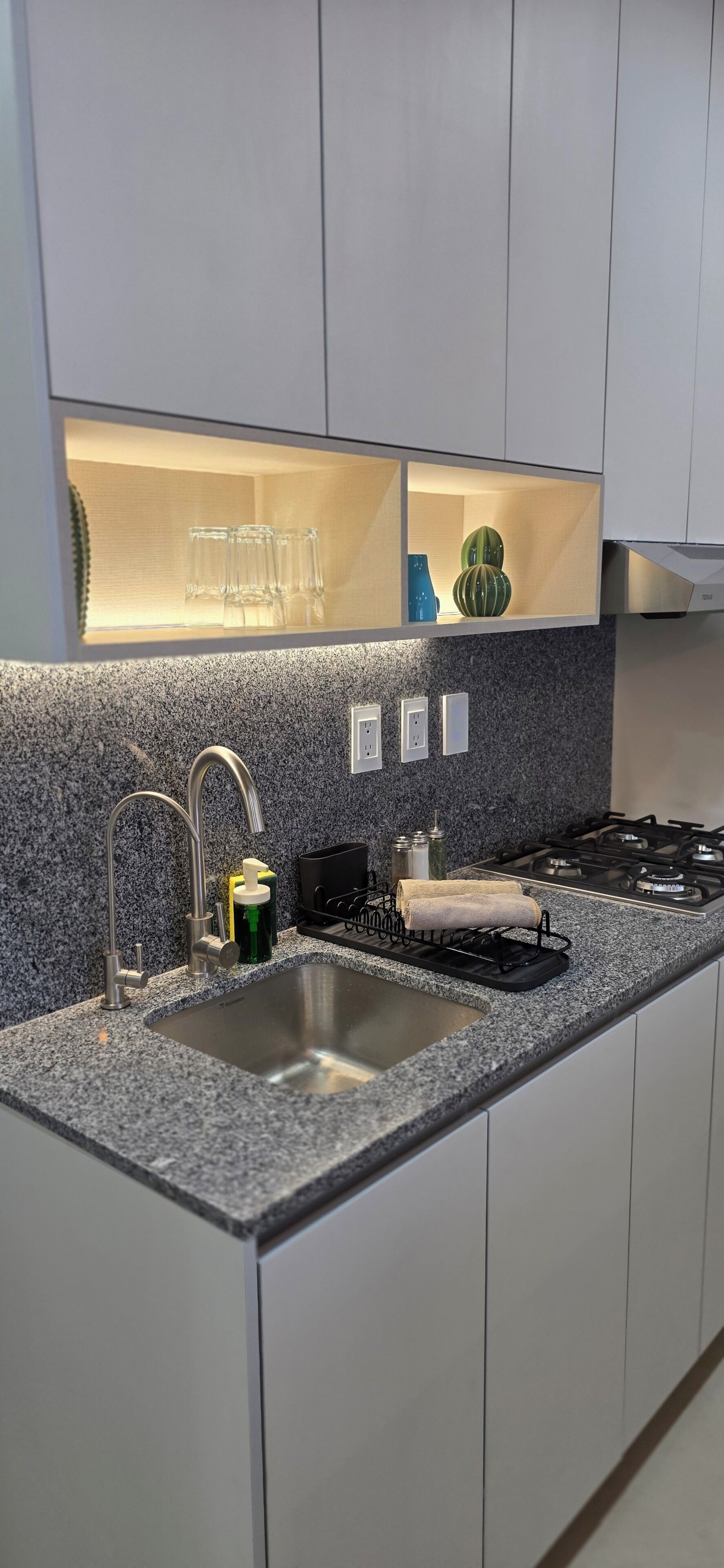 A kitchen with a granite countertop, stainless steel sink, and a built-in oven.