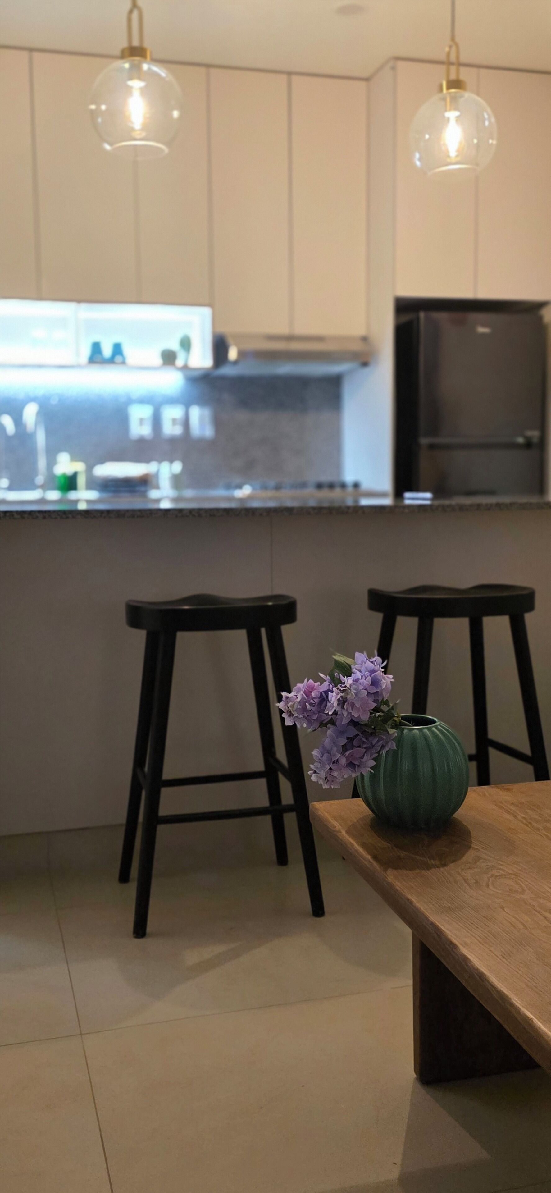 Et moderne køkken med to barstole, et træbord og en vase med blomster.