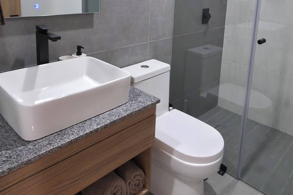 Une salle de bain moderne avec un grand lavabo, des toilettes et une douche à parois de verre.