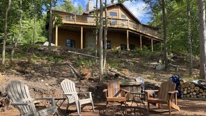 A lodge with a stone chimney, wooden deck, and outdoor seating. - Perfect 4-bedroom lakefront home on North Twin, great for a fun filled getaway! (Phelps)