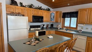 A kitchen with wooden cabinets, a refrigerator, a microwave, a stove, and a sink. - Perfect 4-bedroom lakefront home on North Twin, great for a fun filled getaway! (Phelps)