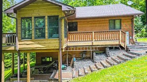 A two-story wooden house with a balcony, a covered porch, and a staircase leading to the upper level. - Perfect 4-bedroom lakefront home on North Twin, great for a fun filled getaway! (Phelps)