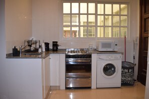 A compact kitchen with a stove, microwave, and washing machine. - Fabulous 3-bedroom apartment with AC in vibrant Buenos Aires (Buenos Aires)
