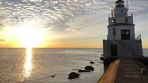 A lighthouse at sunset with a clear sky and calm sea. - Cozy 1-bedroom camper in beautiful Manitowoc, walking distance to Lake Michigan (Manitowoc)