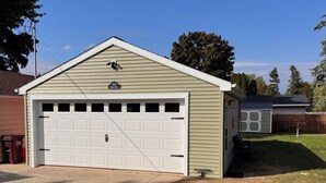 A single-story garage with a white garage door and a small attached shed. - Cozy 1-bedroom camper in beautiful Manitowoc, walking distance to Lake Michigan (Manitowoc)