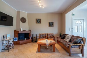 A living room with a fireplace, a sofa set, a coffee table, and a television mounted on the wall. - Effie's Escape Spacious House in Zola (Argostoli)