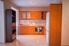A compact kitchen with wooden cabinets, a built-in oven, and a refrigerator. - Effie's Escape Spacious House in Zola (Argostoli)