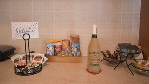 A welcome sign, a bottle of Robol of Cephalonia, snacks, and a bowl of pens on a counter. - Effie's Escape Spacious House in Zola (Argostoli)
