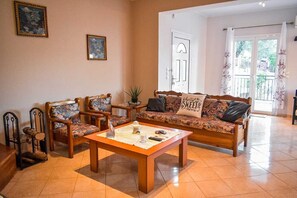 A living room with a sofa, two armchairs, a coffee table, and a door leading to a balcony. - Effie's Escape Spacious House in Zola (Argostoli)