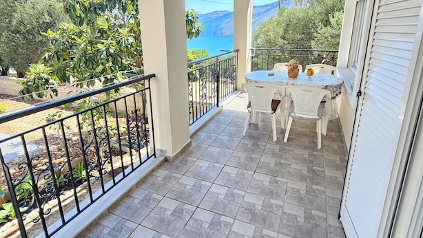 A balcony with a table and chairs, a view of the sea, and a mountainous landscape. - Effie's Escape Spacious House in Zola (Argostoli)
