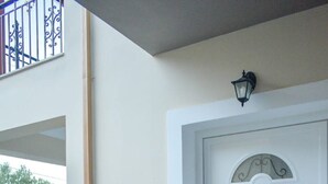 A white door with decorative glass panels and a small light fixture above it. - Effie's Escape Spacious House in Zola (Argostoli)