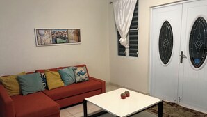 Ein Wohnzimmer mit einem roten Sofa, einem weißen Couchtisch und einem gerahmten Stadtbild an der Wand.