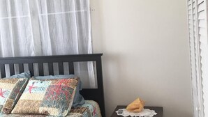 Ein Schlafzimmer mit einem Bett, einem Nachttisch, einer Klimaanlage und einem Fenster mit Jalousien.