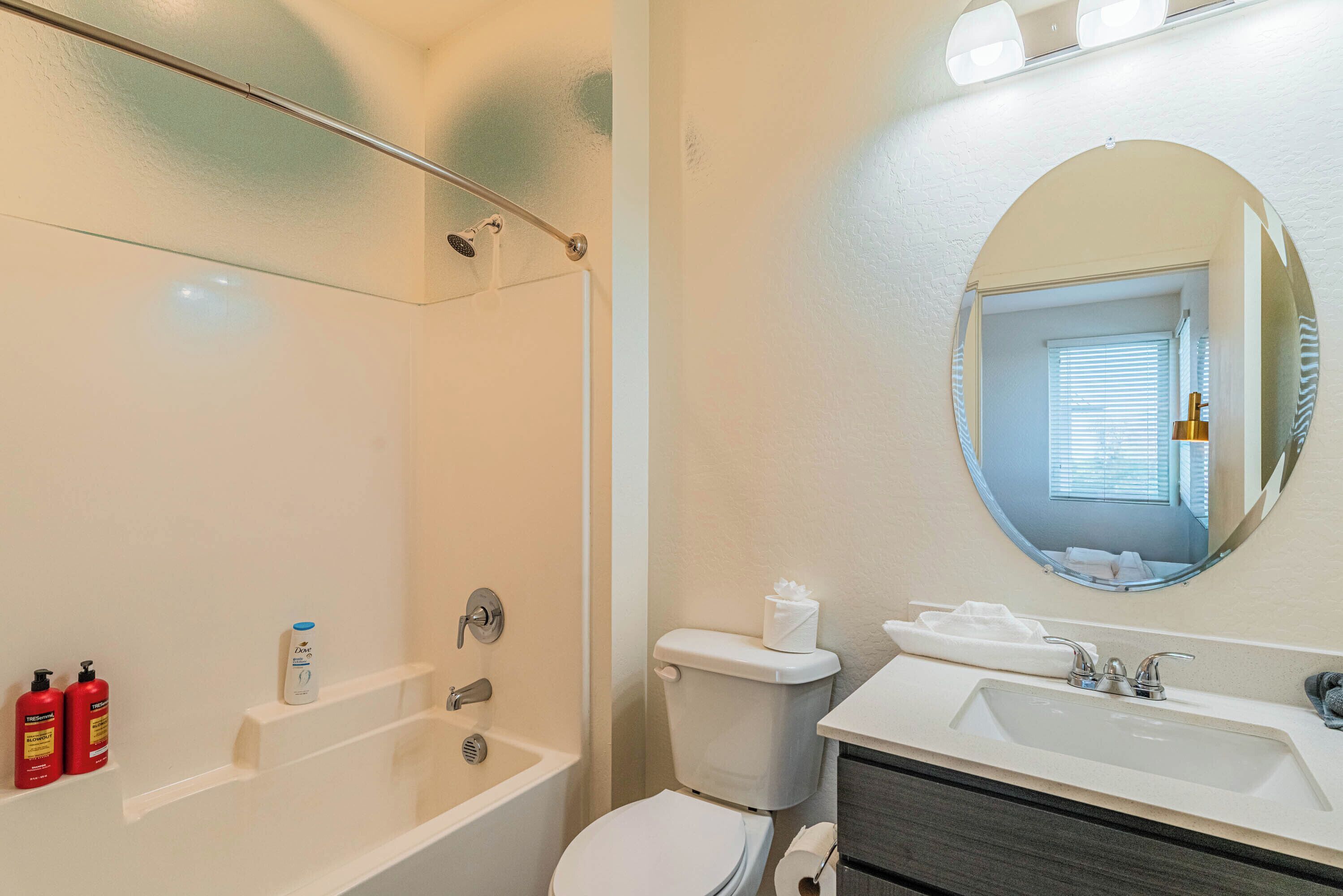 A bathroom with a bathtub, toilet, sink, and a mirror.
