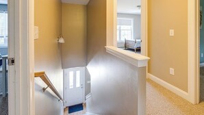 A hallway with a white door, a small window, and a mirror on the wall. - •	Quiet 3BR Home Close to Biddeford Beaches (Biddeford)