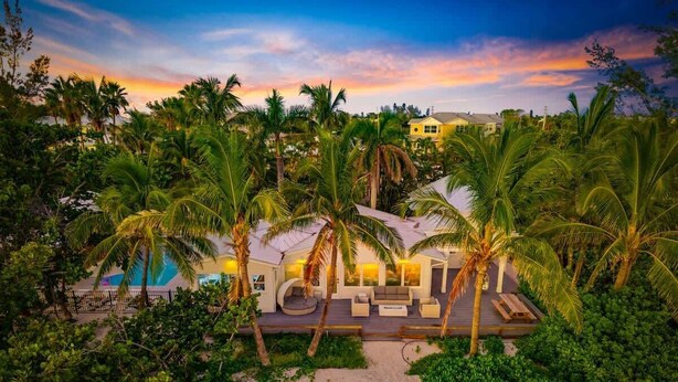 Un resort con piscina, area salotto all'aperto e palme.