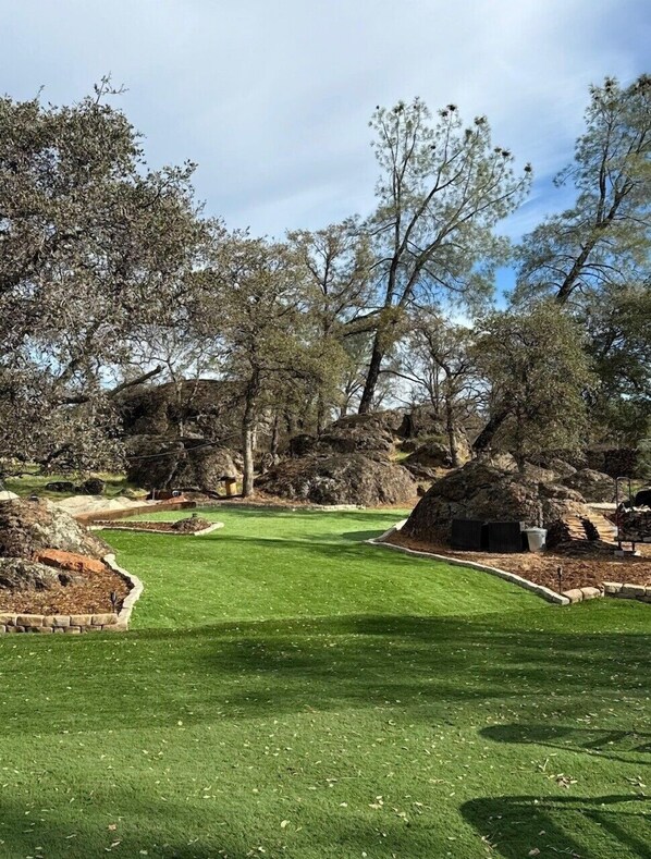 Un campo de golf bien cuidado con un camino despejado, rodeado de árboles y rocas.