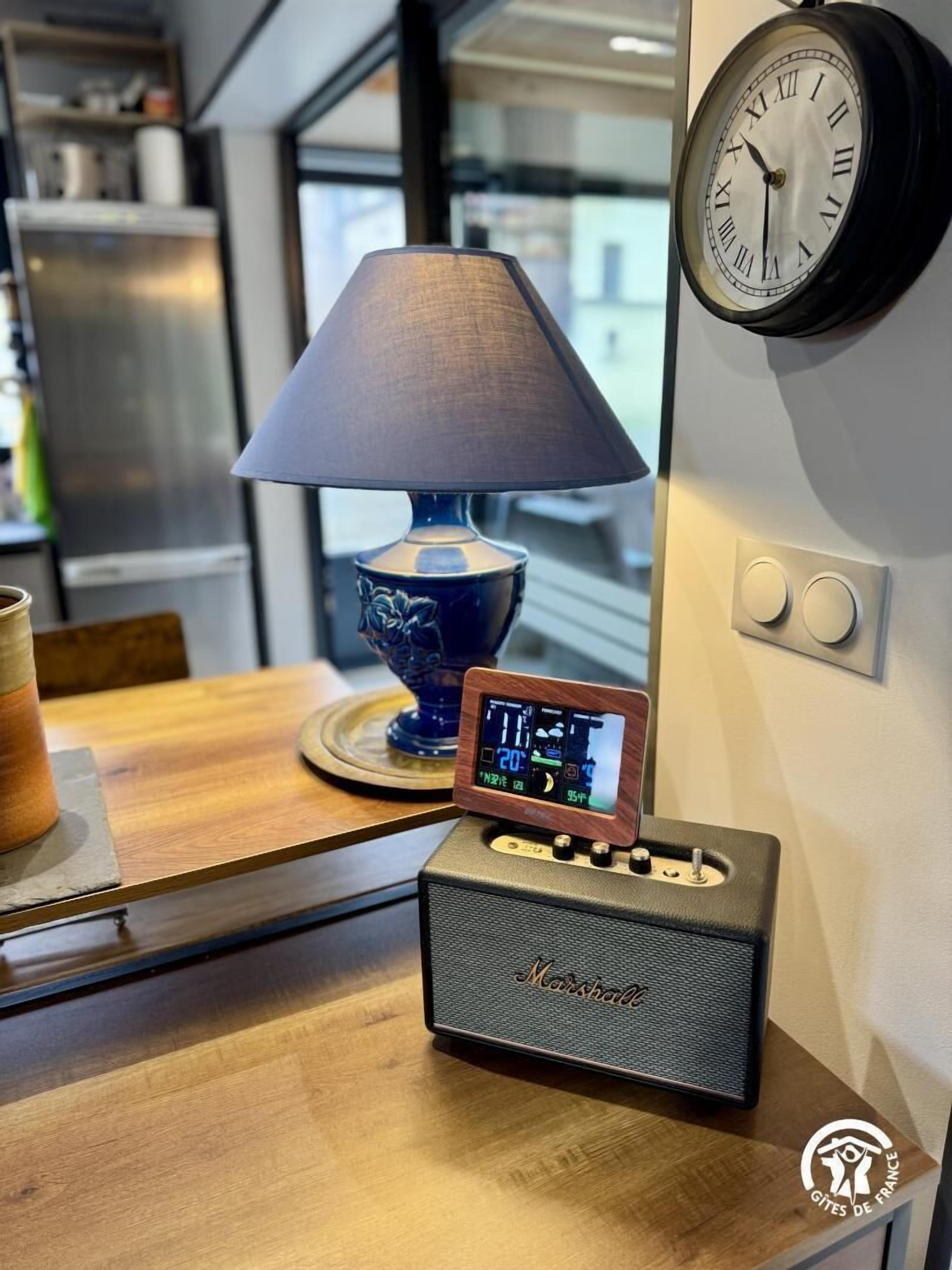 A kitchen with a digital clock, a lamp, and a coffee maker on the counter.