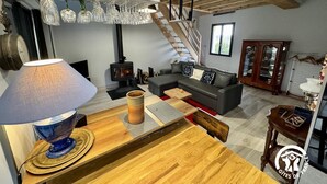En hyggelig stue med sofa, sofabord, lampe, et træspisebord, bogreol og en trappe, der fører op til et andet niveau.