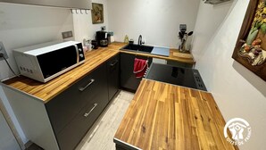Cocina compacta con microondas, lavamanos y encimera de madera.