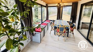 A dining area with a wooden ceiling, a table with a floral tablecloth, and cushioned benches. - Grand Sissou - BUGARACH (BUGARACH)