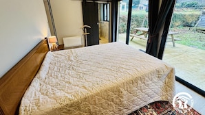 A bedroom with a large bed, a window, and a view of the outdoors. - Grand Sissou - BUGARACH (BUGARACH)