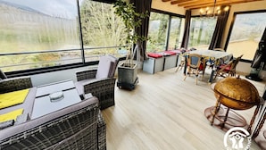 A spacious room with large windows, wicker furniture, a dining table, and a globe. - Grand Sissou - BUGARACH (BUGARACH)