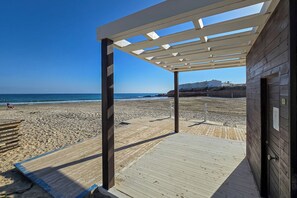 Eine am Strand stehende Holzkonstruktion mit überdachter Terrasse und Blick auf das Meer.