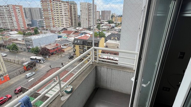 Ein Balkon mit Blick auf eine Stadtlandschaft, darunter Hochhäuser und eine Straße mit Fahrzeugen.