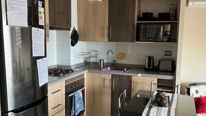 Eine moderne Küche mit einem Edelstahl-Kühlschrank, Holzschränken, einem Gasherd und einem Essbereich mit blauem Stuhl und Tisch.