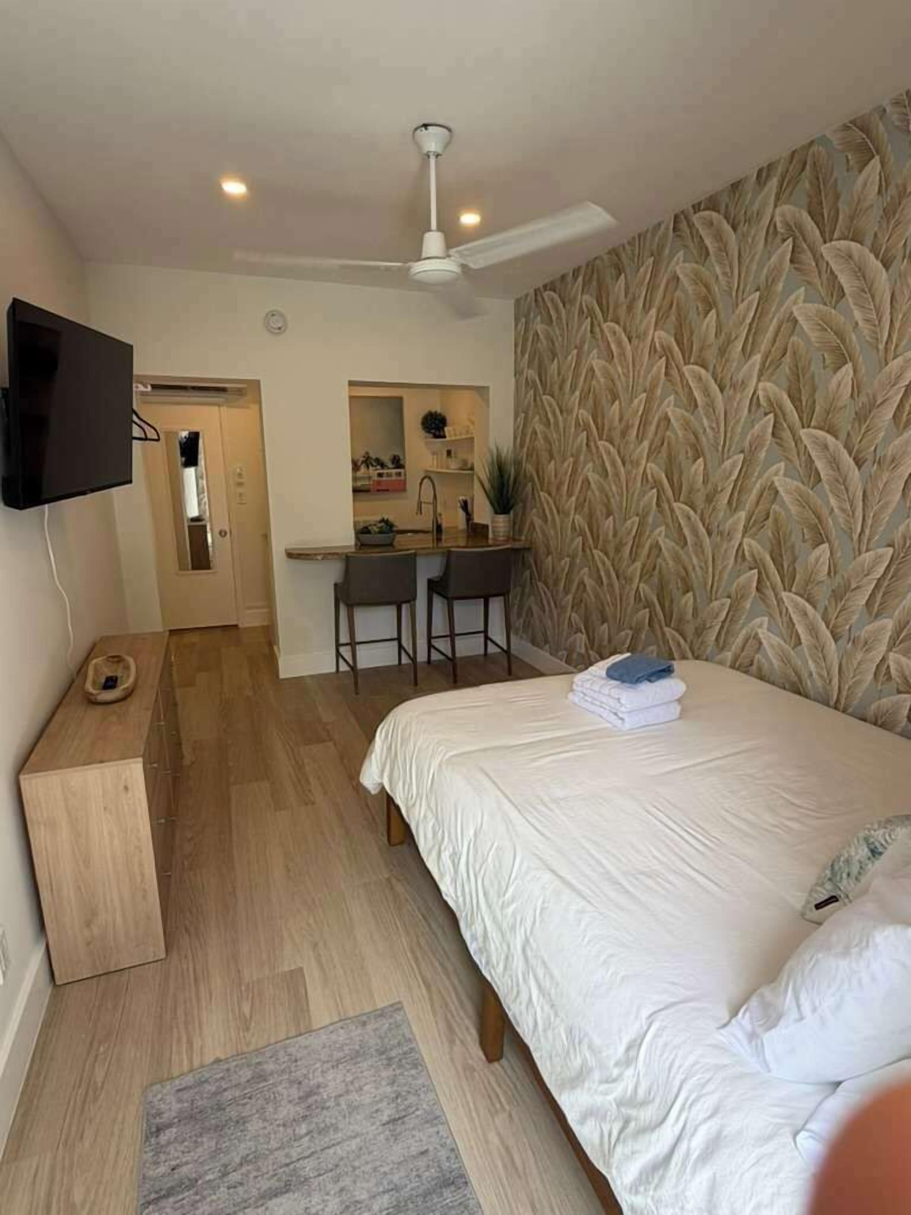 A bedroom with a bed, a desk, and a television.