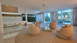Ein modernes Wohnzimmer mit einem weißen Sofa, beigen Sesseln und einem Glastisch.