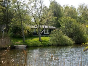 A house by a lake with a boat docked nearby. - Nature oasis with private lake near beach (Fårevejle)
