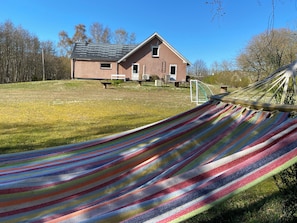 A hammock in a grassy area with a house in the background.