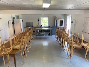 A kitchen with a central island, chairs arranged in rows, and a dining table.