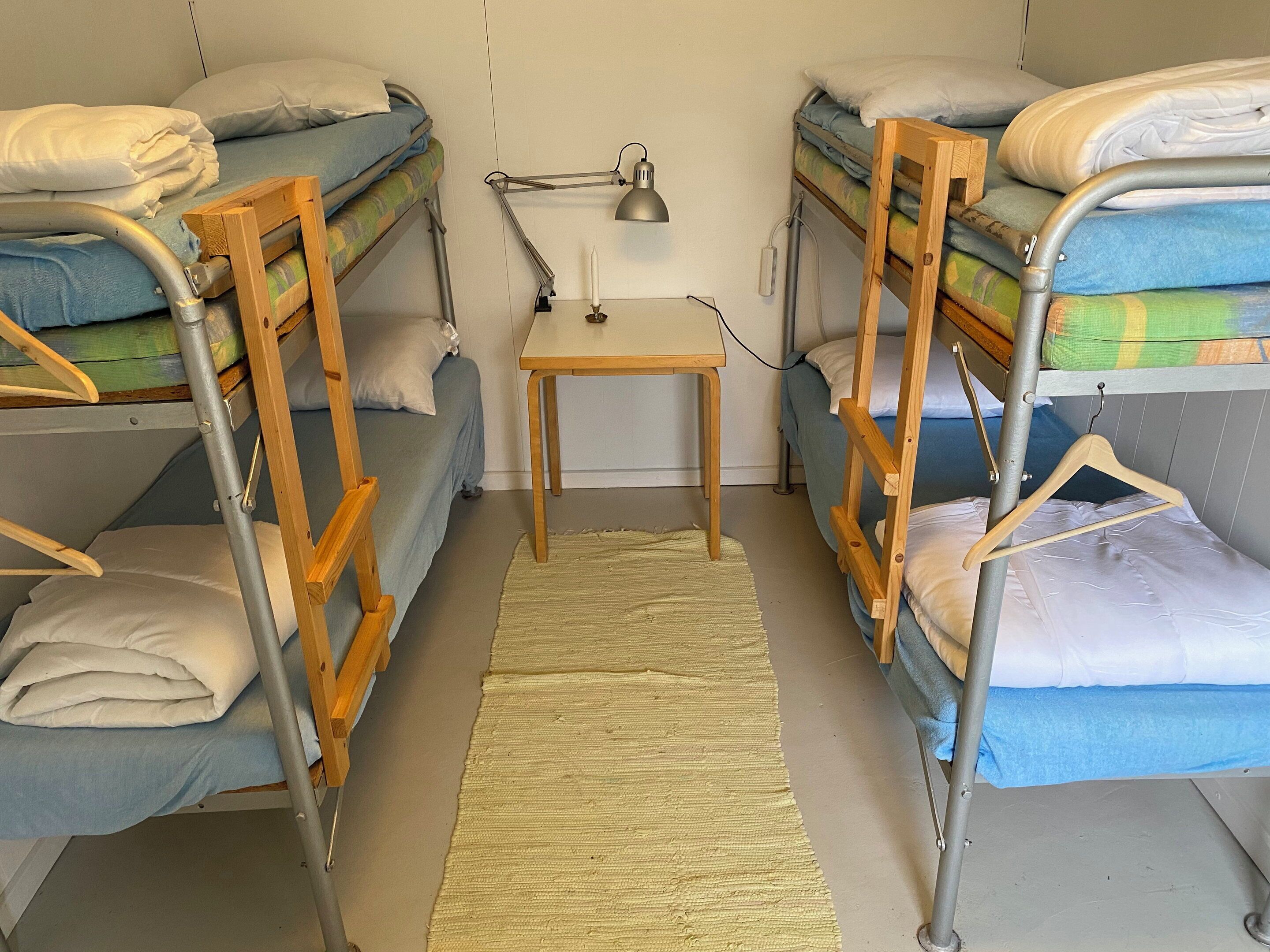 Quarto com beliche, escrivaninha, luminária e tapete pequeno.