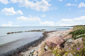Eine felsige Küstenlinie mit Kieselsteinen und blauem Himmel.