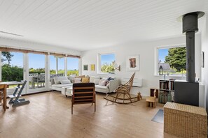 A spacious living area with a sofa, rocking chair, and a fireplace. - Cozy family holiday home with beautiful view (Fårevejle)