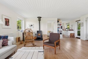 Ein geräumiges Wohnzimmer mit Kamin, Essbereich und einer Küche mit weißen Schränken.