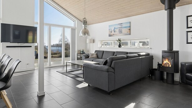 Een moderne woonkamer met een grijze modulaire bank, een zwarte open haard en een groot raam.