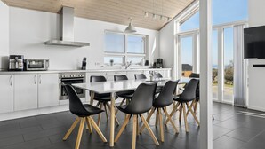 Een moderne keuken met een eethoek, grote ramen en uitzicht op de omgeving.