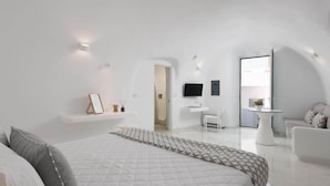 A modern hotel room with a large bed, a desk, and a seating area. - White Concept Caves - Adults Only (Santorini)