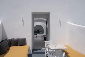 A modern hotel room with a sofa, a small table, and a view into the dining area. - White Concept Caves - Adults Only (Santorini)