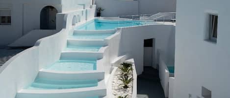 A white building with a blue pool and steps leading to a door.