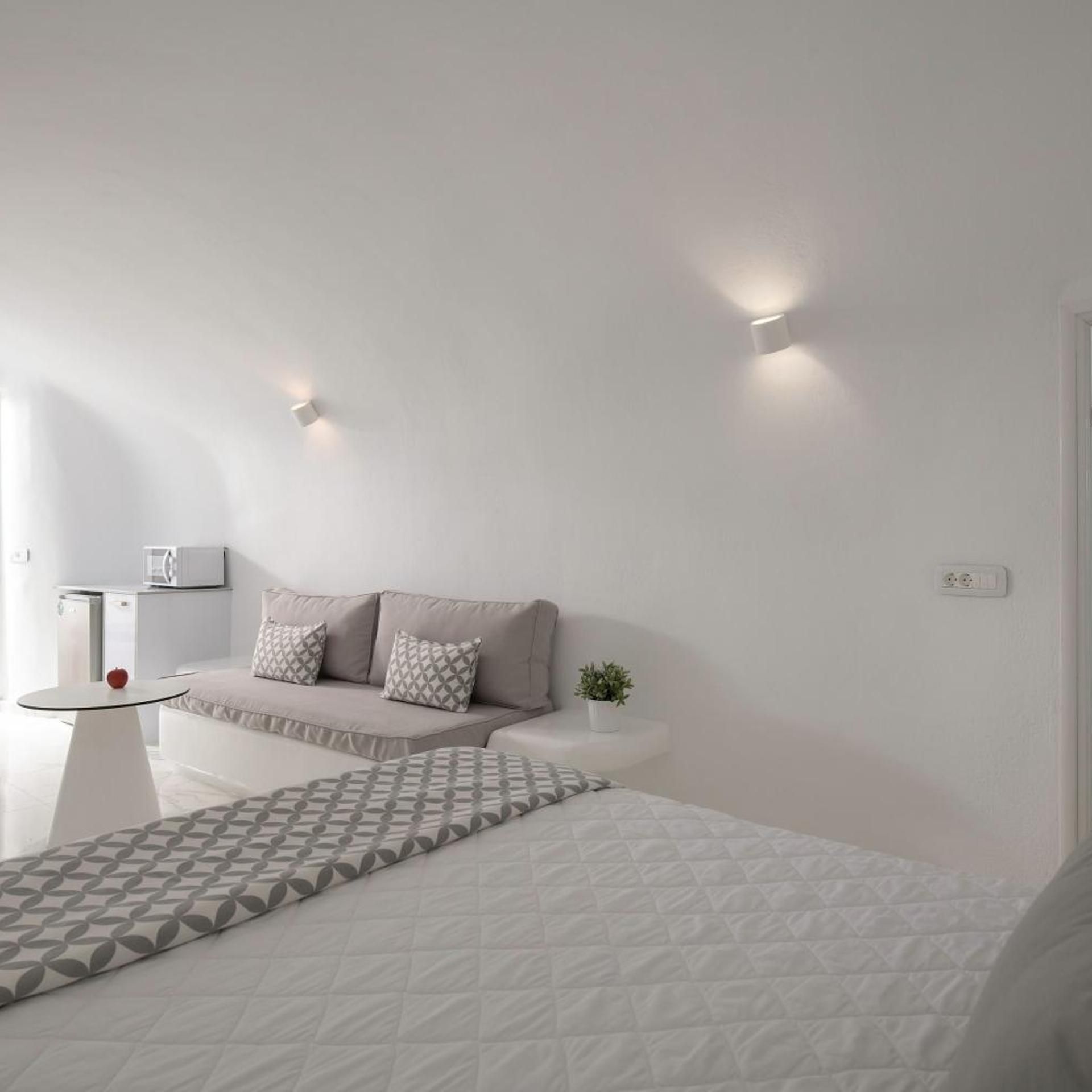 A minimalist bedroom with a bed, bedside table, and a small potted plant.